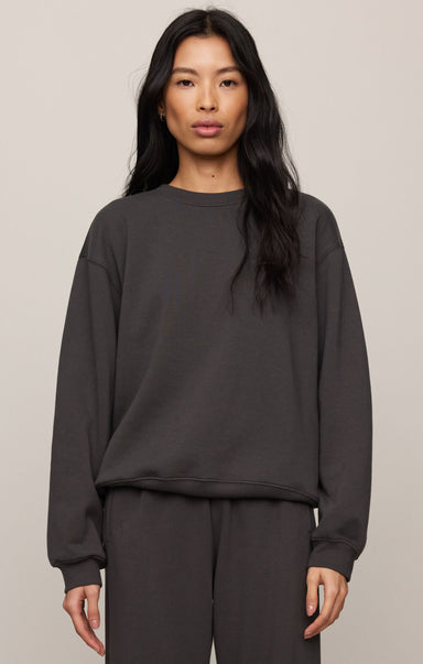 Person wearing a dark gray sweatshirt and pants on a beige background