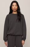 Person wearing a dark gray sweatshirt and pants on a beige background