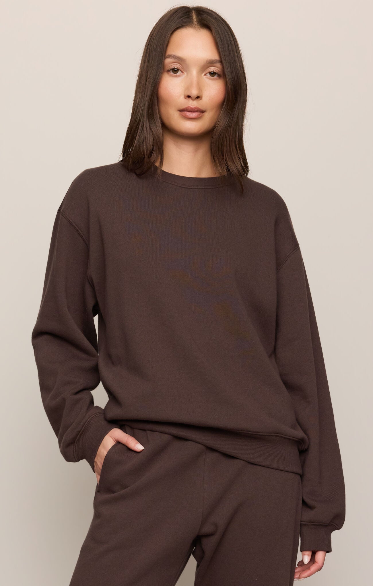Person wearing a brown sweatshirt and pants on a plain background