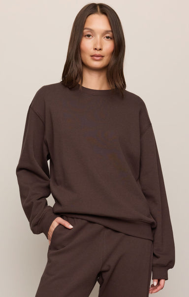 Person wearing a brown sweatshirt and pants on a plain background