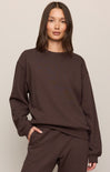 Person wearing a brown sweatshirt and pants on a plain background