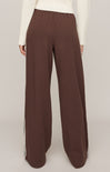 Brown wide-leg pants worn with a white top on a plain background