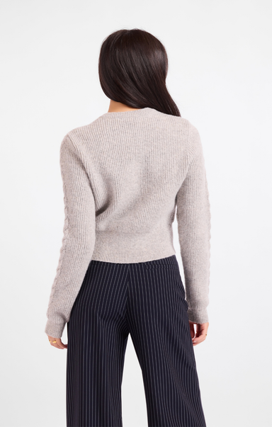 Person wearing a light gray sweater and dark pinstripe pants on a white background