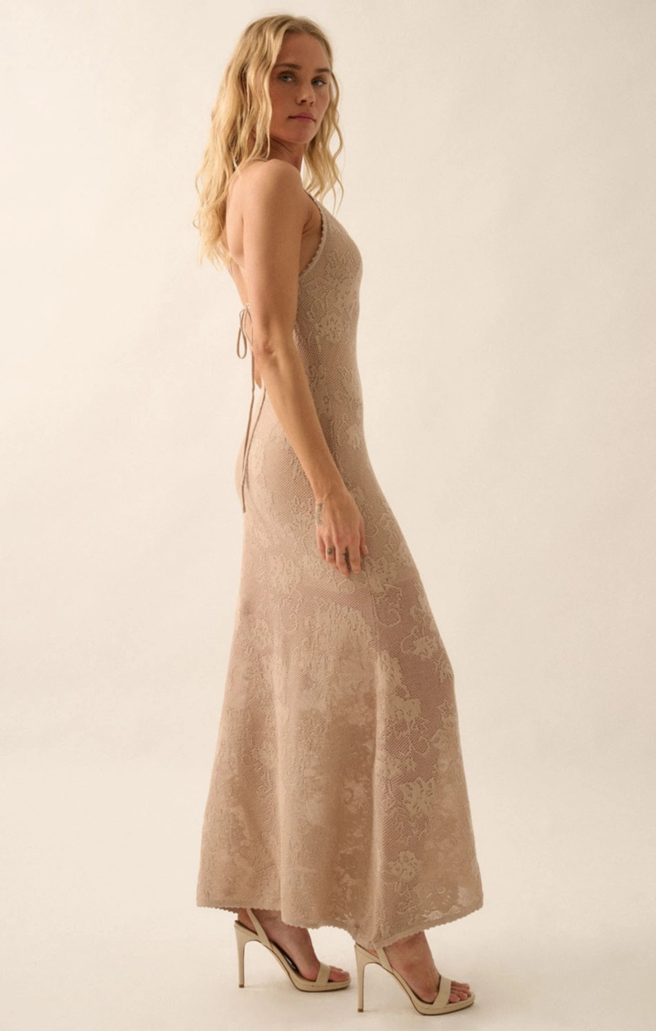 Woman wearing a beige sleeveless dress against a white background