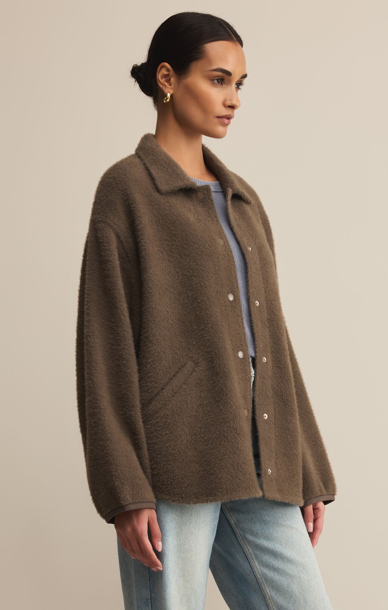 Woman wearing a brown coat against a beige background