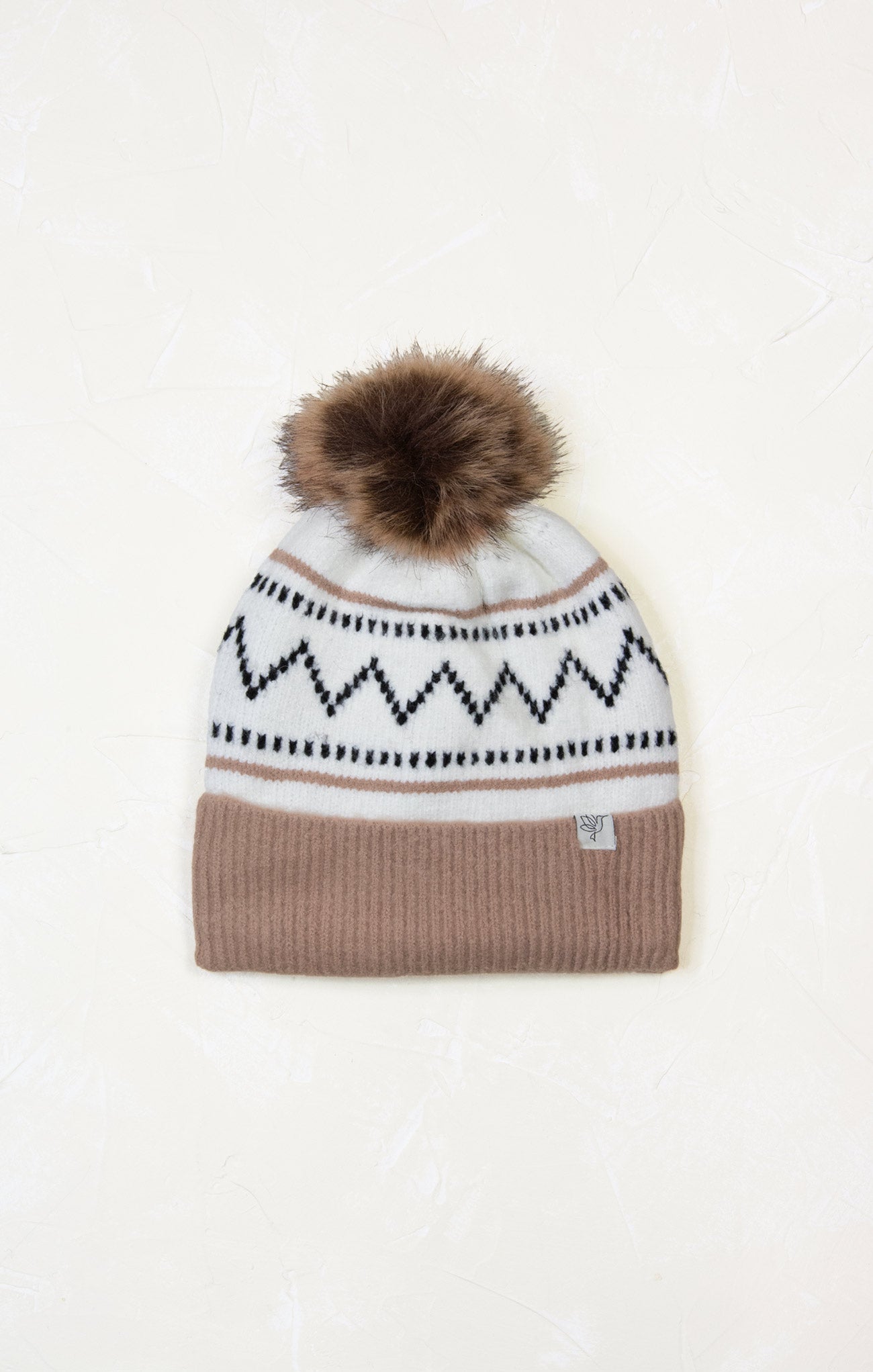 Knitted beanie with a patterned band and fur pom-pom on a white background