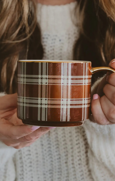 Person holding a plaid mug with a blurred background