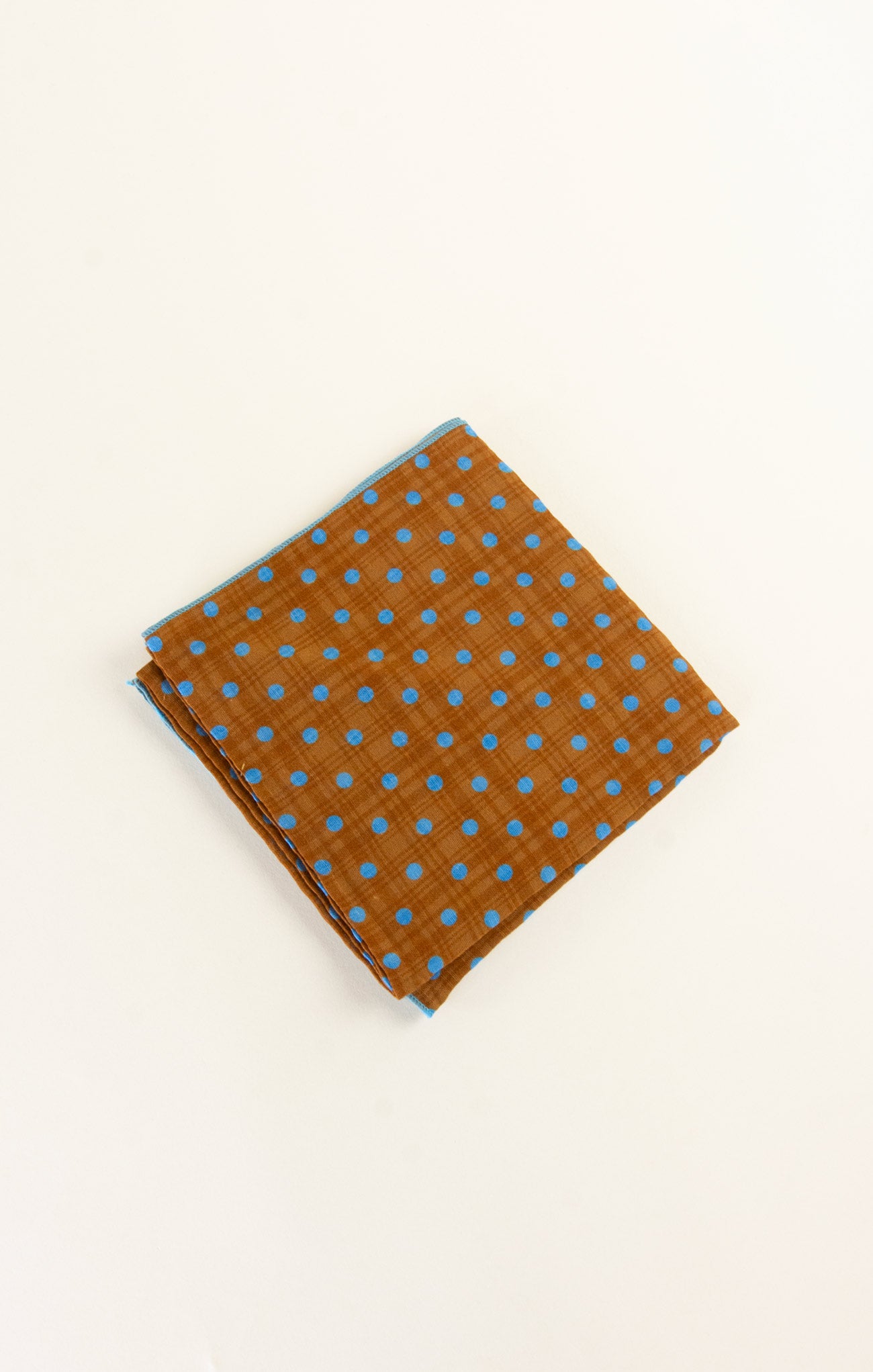 Brown fabric with blue polka dots on a beige background