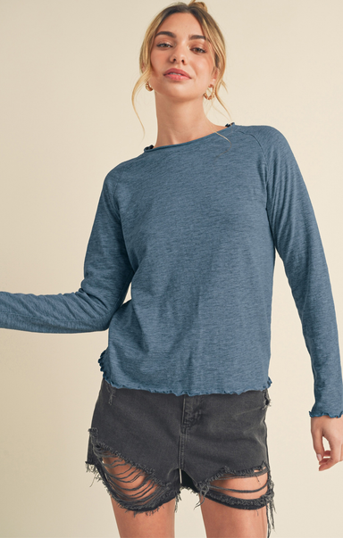 Woman wearing a blue long-sleeve top and black shorts on a beige background
