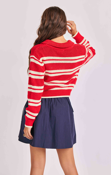 Person wearing a red and white striped sweater and navy skirt on a light gray background