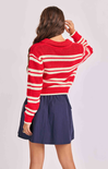 Person wearing a red and white striped sweater and navy skirt on a light gray background