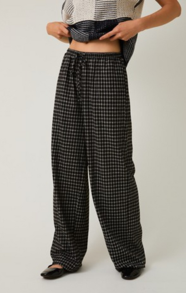 Person wearing black and white checkered pants on a plain background