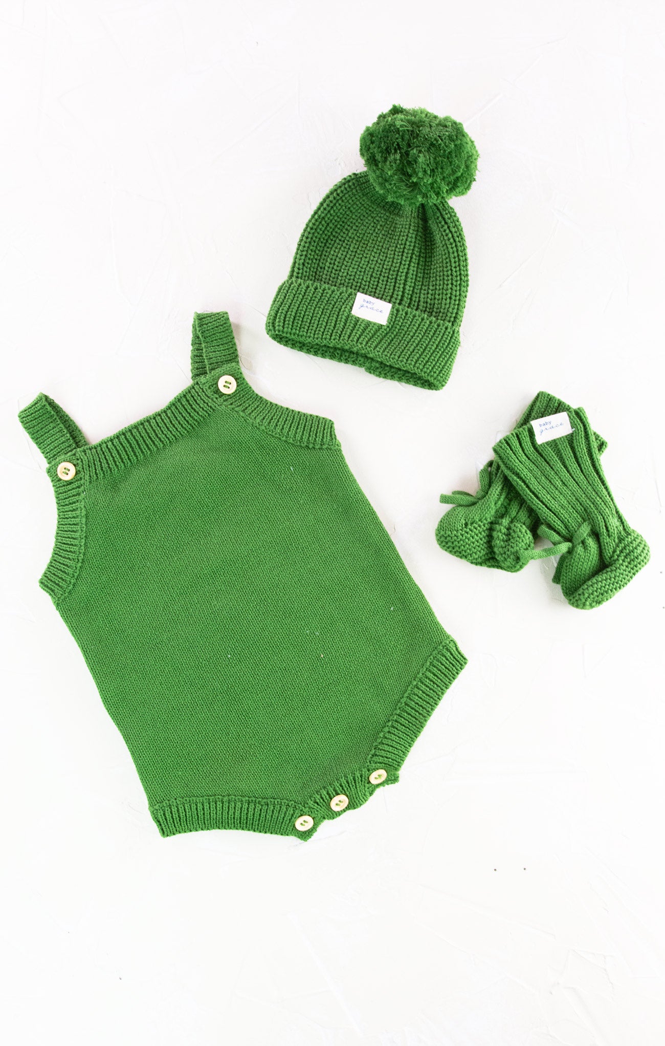 Green baby romper with matching hat and gloves on a white background