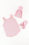 Pink baby romper, hat, and booties set on a white background