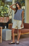 Woman in a striped shirt and shorts standing outdoors on a patio.