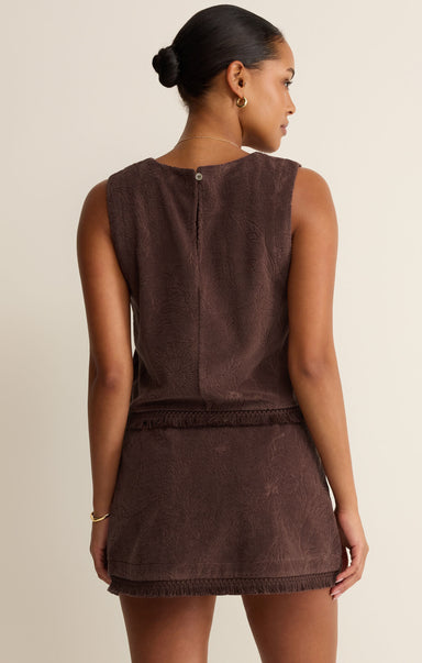 Woman wearing a brown sleeveless dress against a neutral background