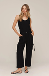 Woman wearing a black sleeveless jumpsuit on a beige background