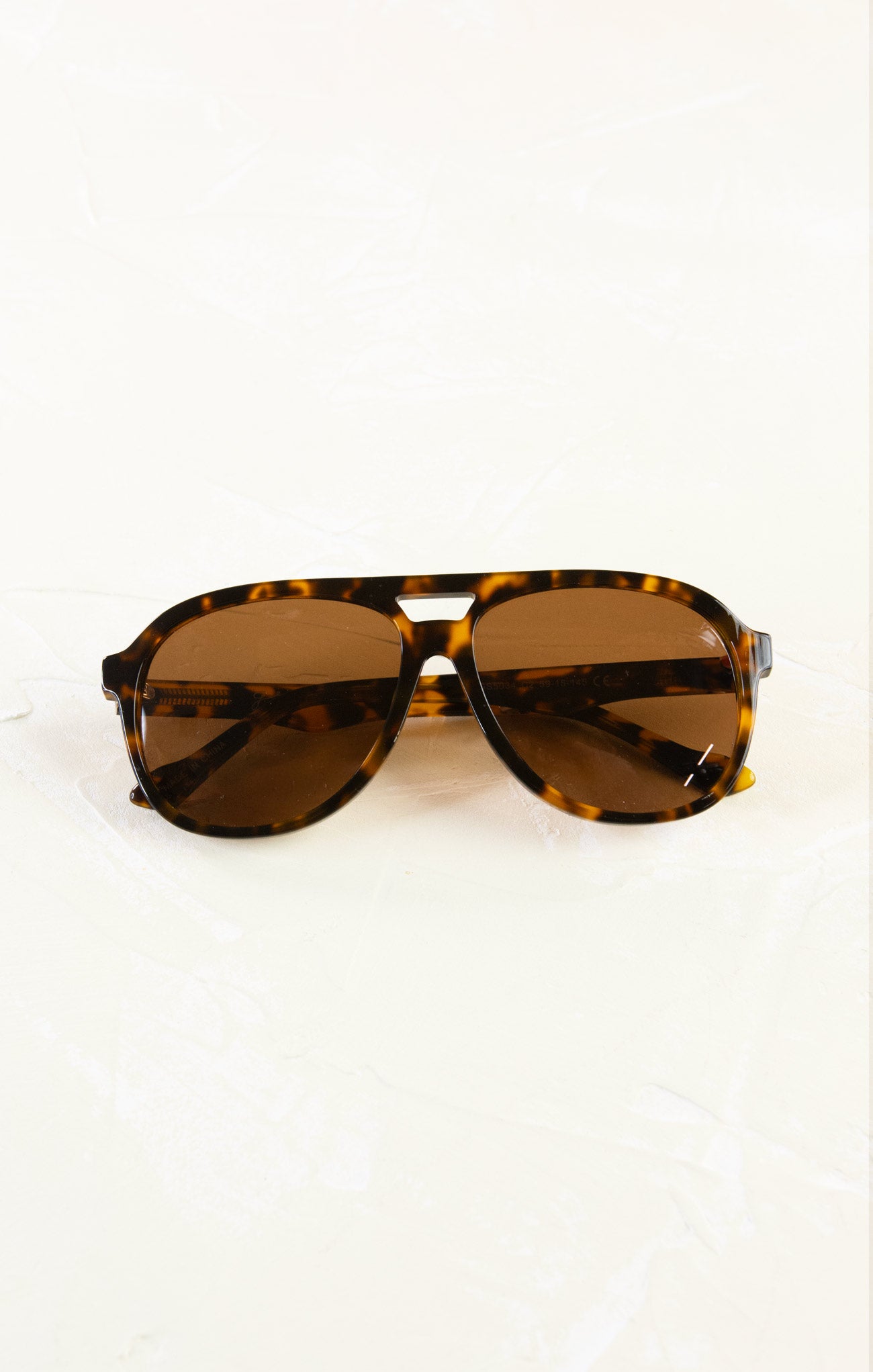 Tortoiseshell sunglasses with brown lenses on a white background