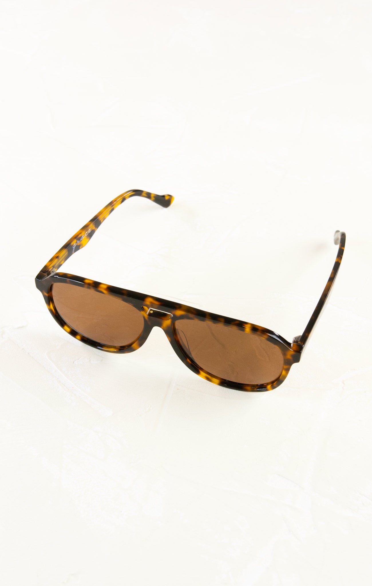 Sunglasses with tortoiseshell frame and brown lenses on a white background