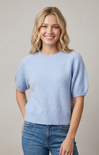 Woman wearing a light blue sweater and jeans against a plain background