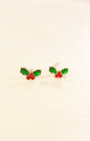Pair of earrings with green and red designs on a beige background