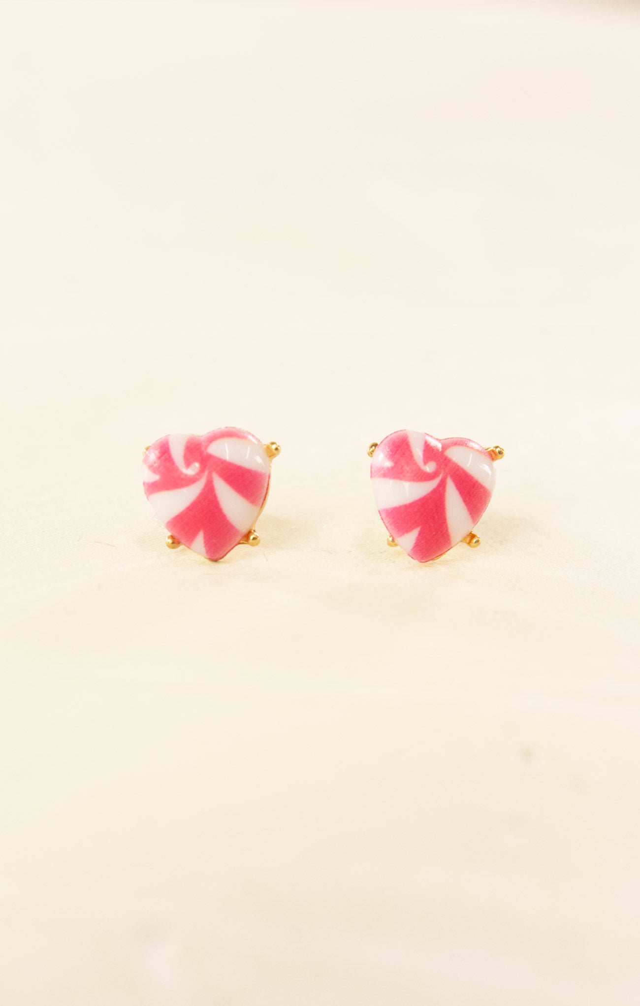 Pink and white striped earrings on a beige background