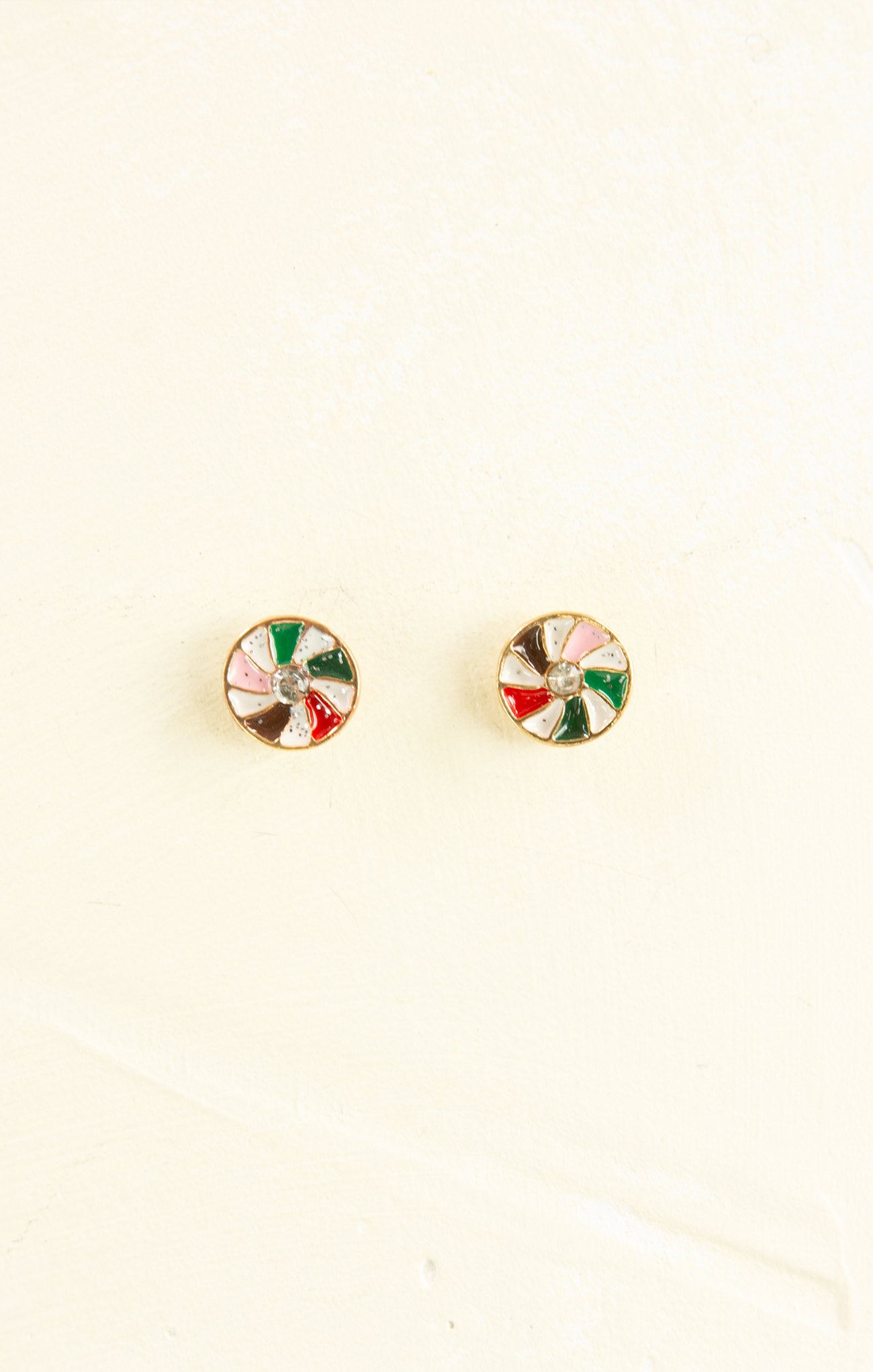 Round earrings with colorful designs on a beige background