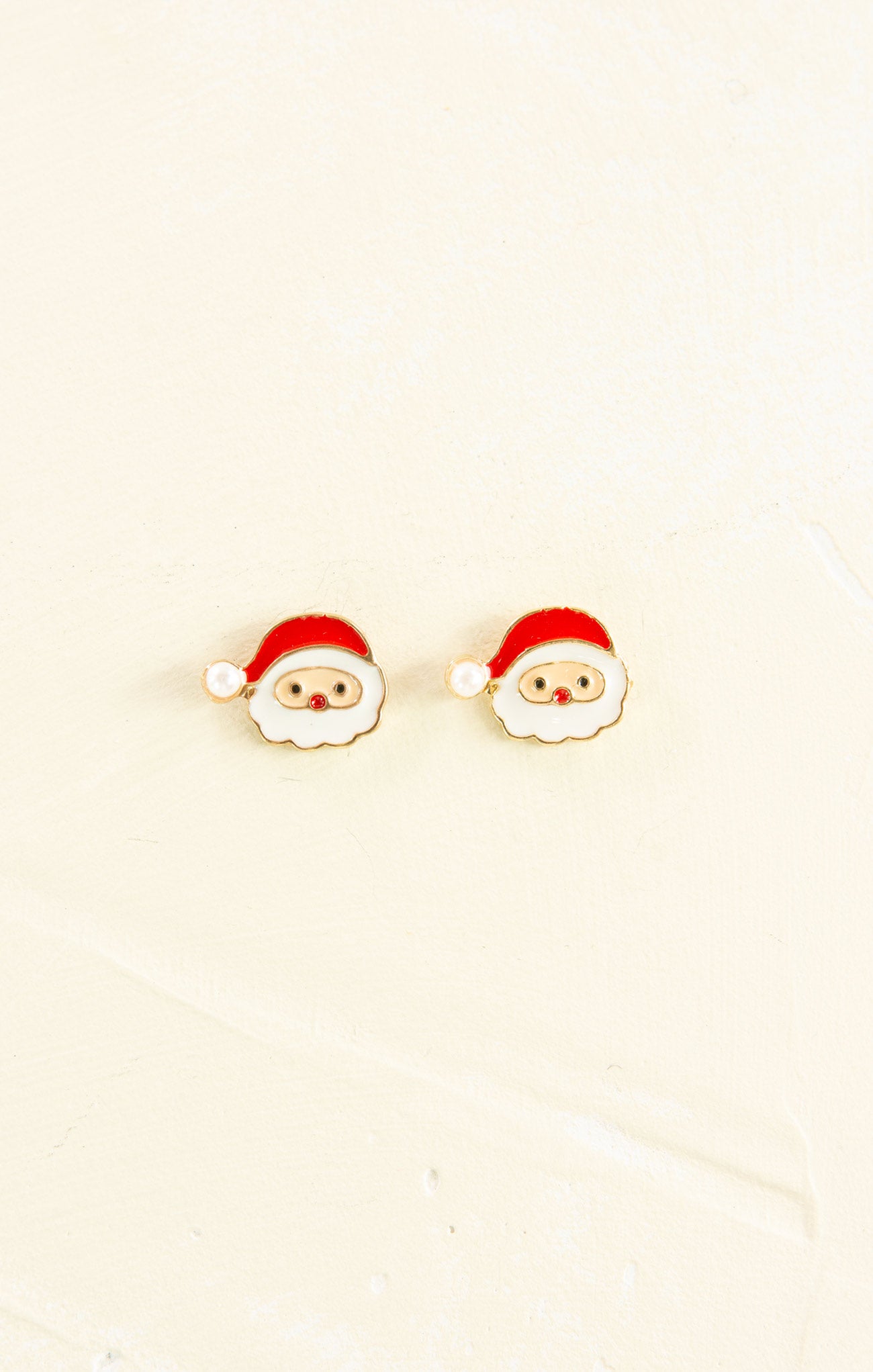 Santa Claus-themed earrings on a beige background