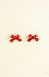 Red bow-shaped earrings on a beige background