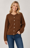 A woman wearing a brown button-front cardigan sweater and blue jeans, standing against a light gray studio background.