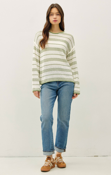 Woman wearing a striped sweater and blue jeans on a white background