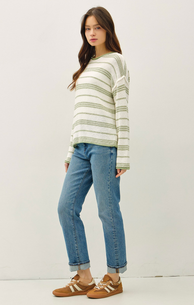 Woman wearing a striped sweater and blue jeans against a white background