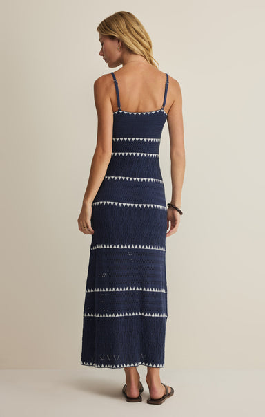 Woman wearing a navy blue dress with white patterns on a beige background