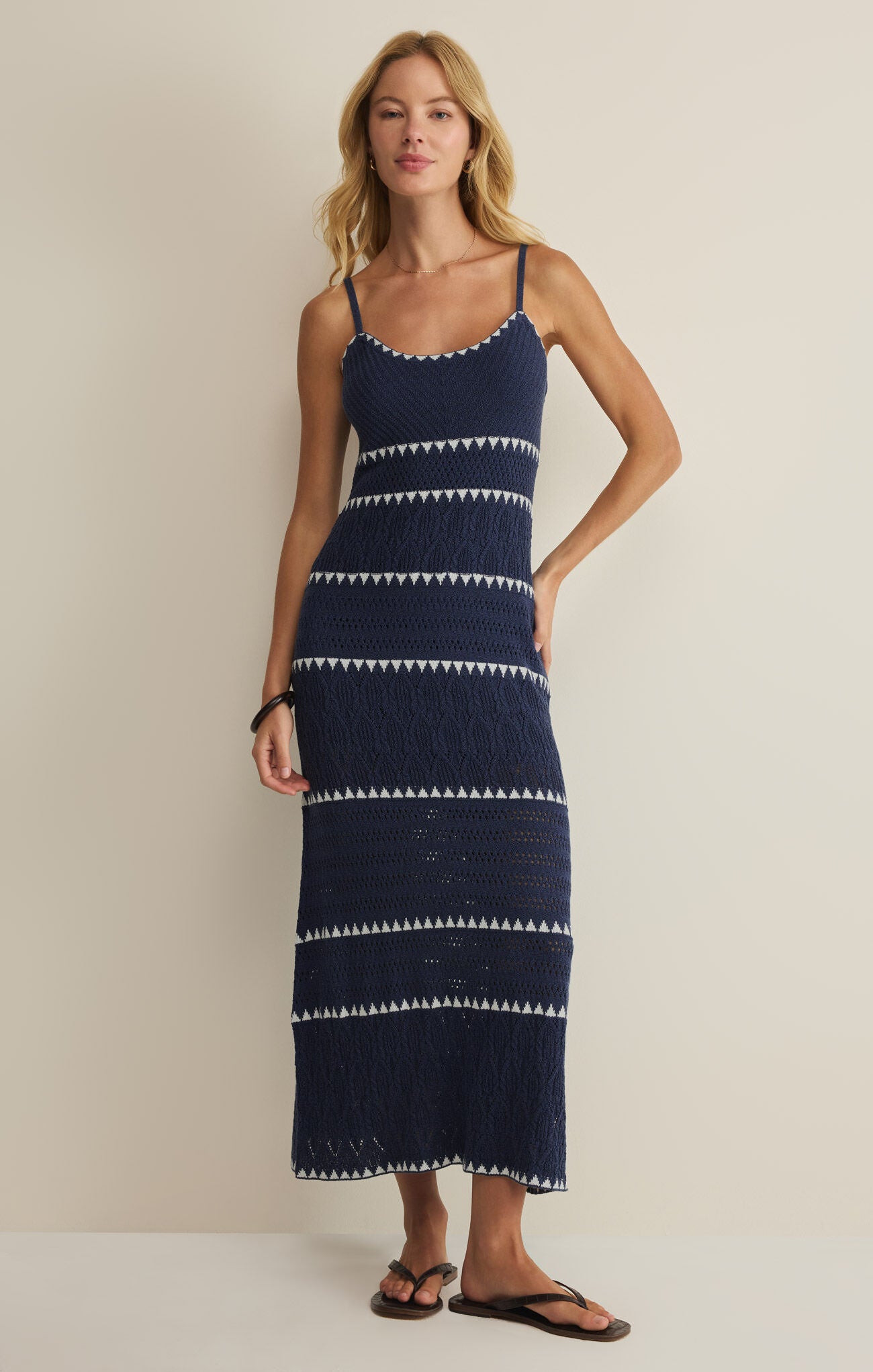 Woman wearing a navy blue dress with white patterns against a beige background