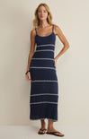Woman wearing a navy blue dress with white patterns against a beige background