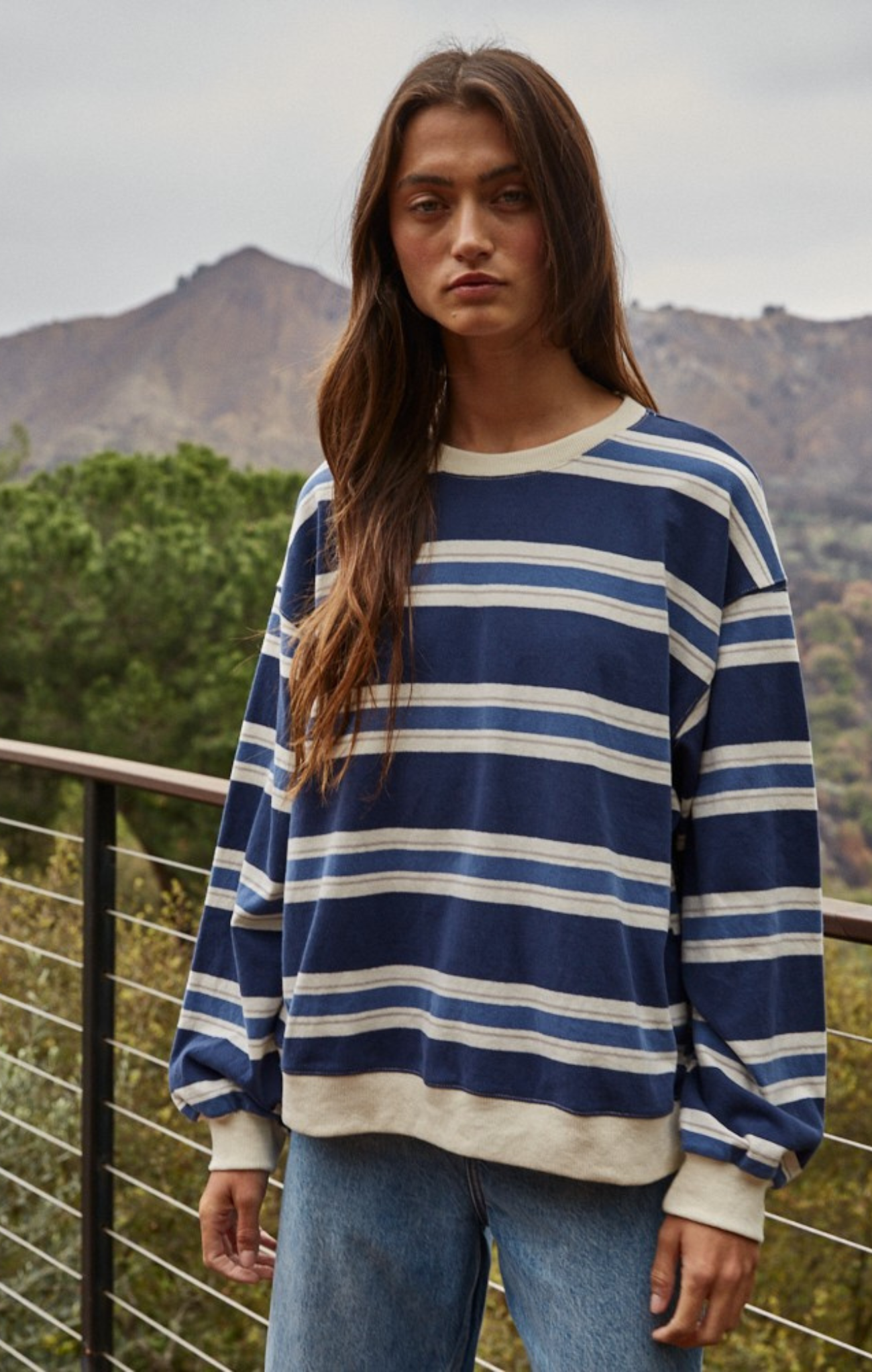 Woman wearing a blue and white striped sweater with mountains in the background
