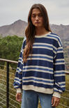 Woman wearing a blue and white striped sweater with mountains in the background