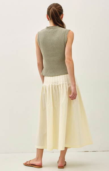 Woman wearing a green sleeveless top and yellow skirt on a white background