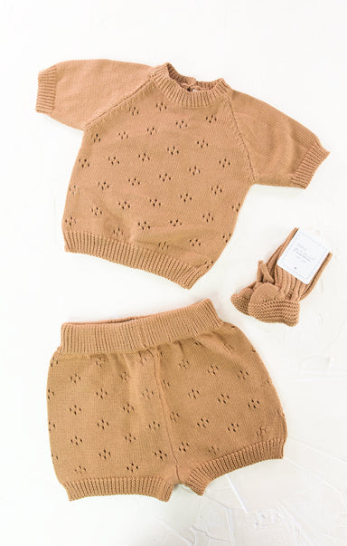 Tan knit outfit with shorts and matching booties on a white background