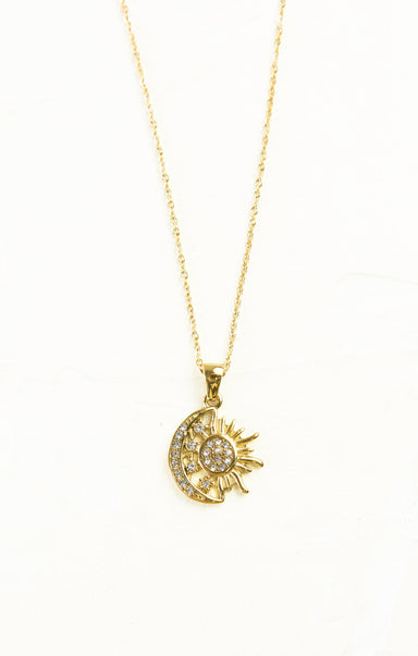 Gold necklace with a sun and moon pendant on a white background