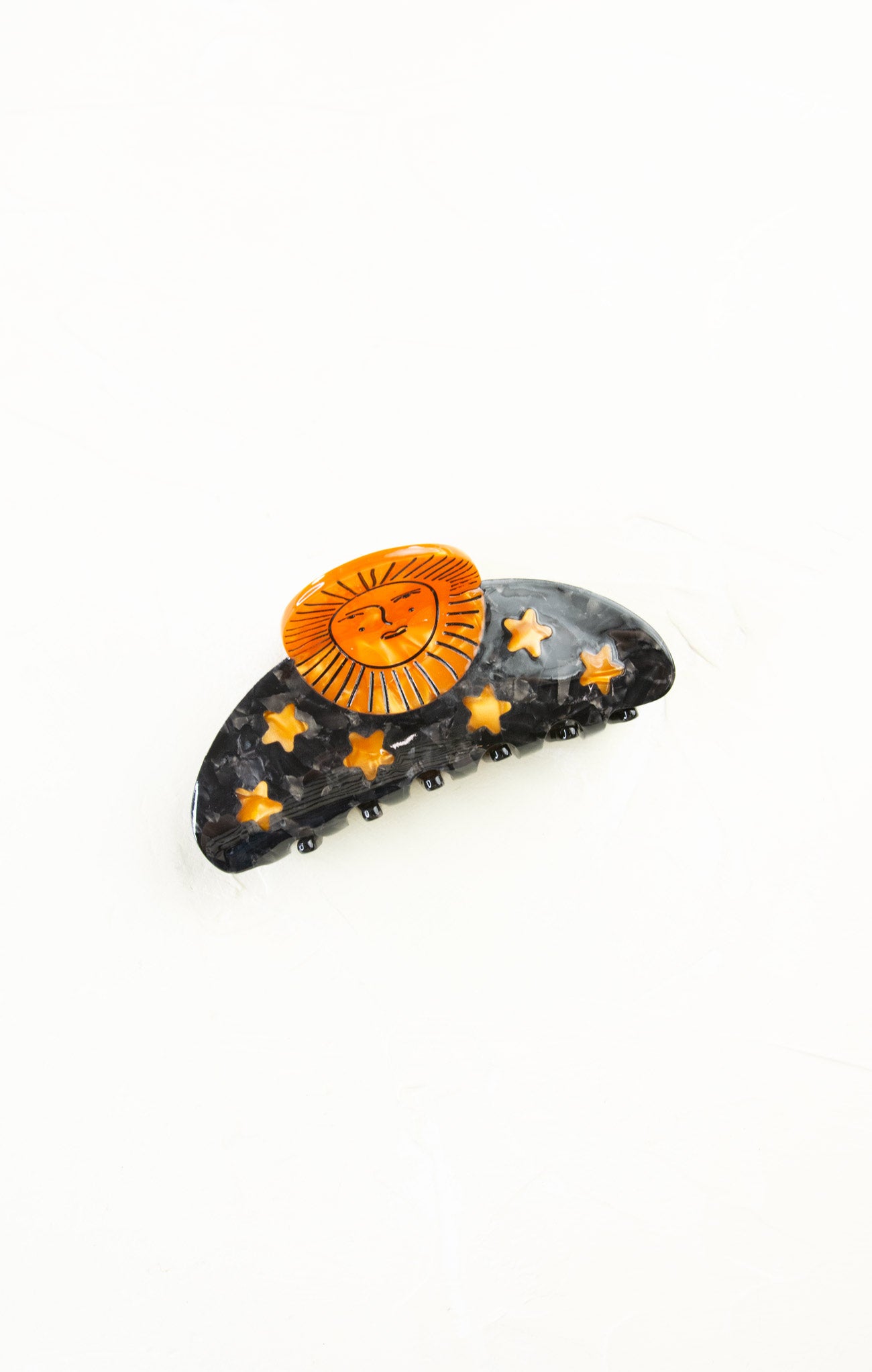 Decorative hair clip with sun and star designs on a white background