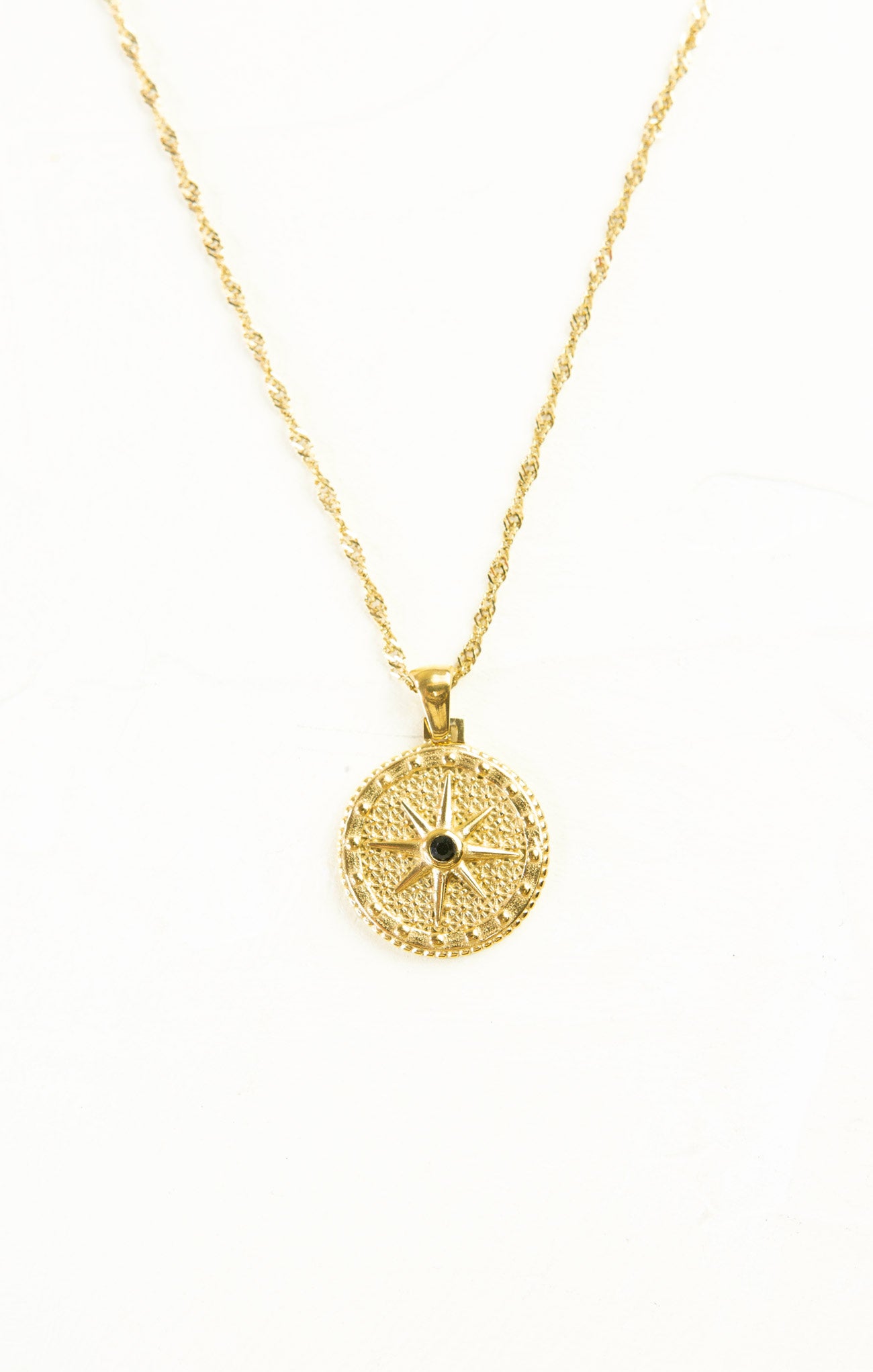 Gold necklace with a circular pendant on a white background