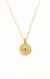 Gold necklace with a circular pendant on a white background