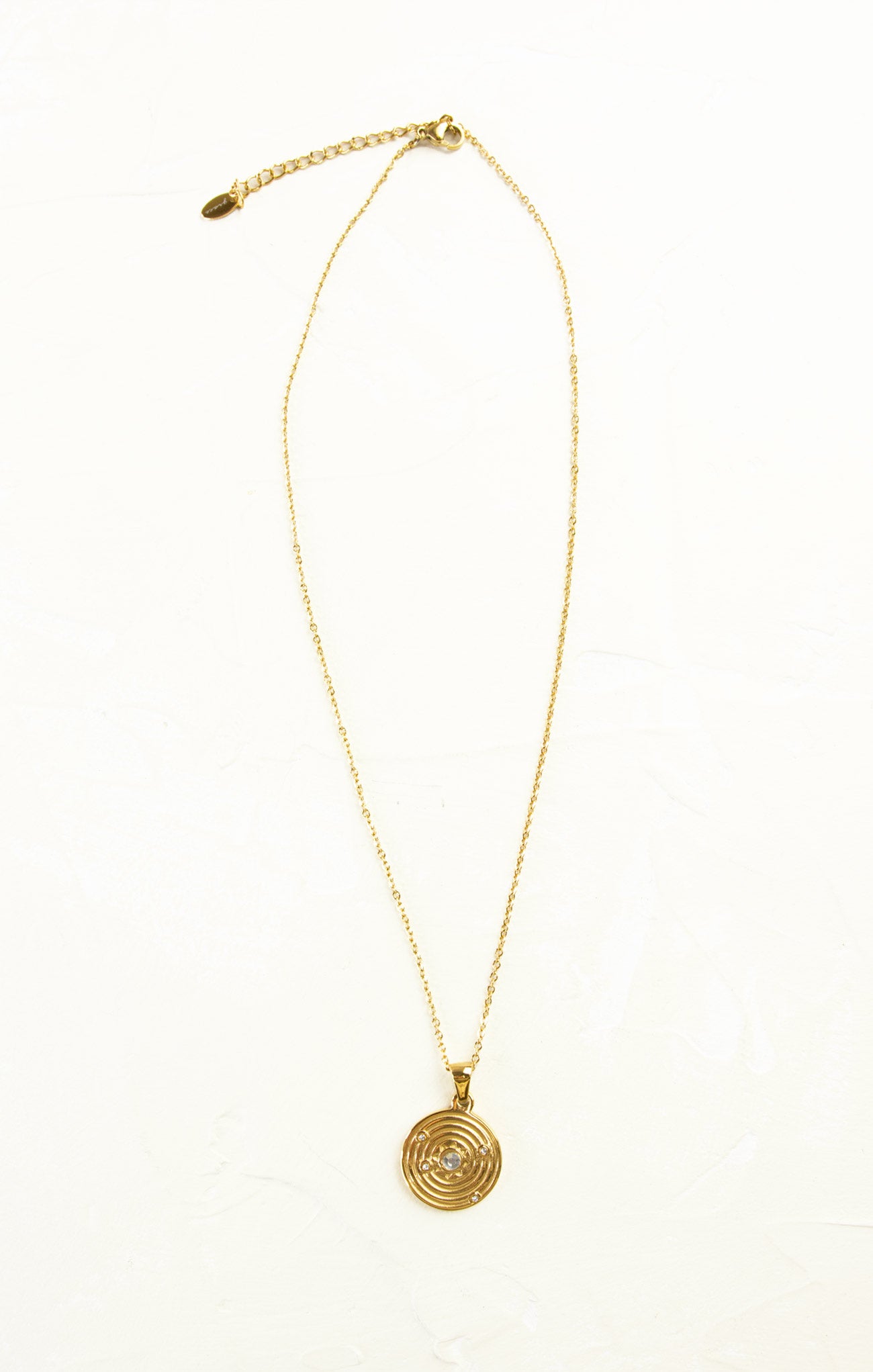 Gold necklace with a circular pendant on a white background