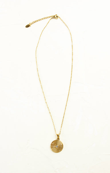 Gold necklace with a circular pendant on a white background