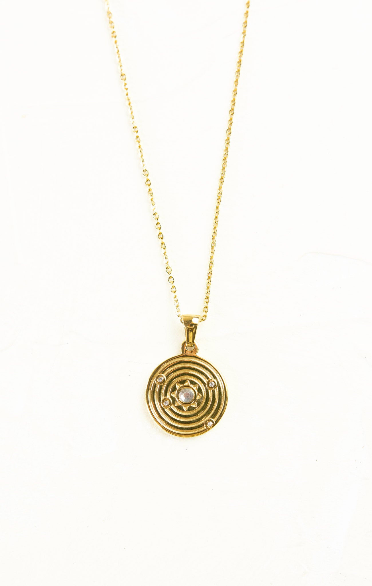 Gold necklace with a circular pendant on a white background