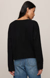 Person wearing a black sweater and blue jeans against a plain background
