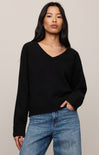 Woman wearing a black sweater and blue jeans against a plain background