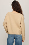 Person wearing a beige sweater and blue jeans on a plain background