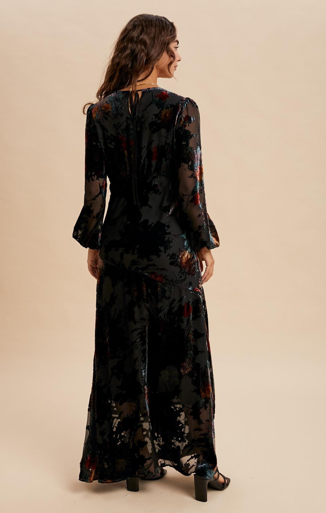 Woman wearing a black floral dress against a beige background